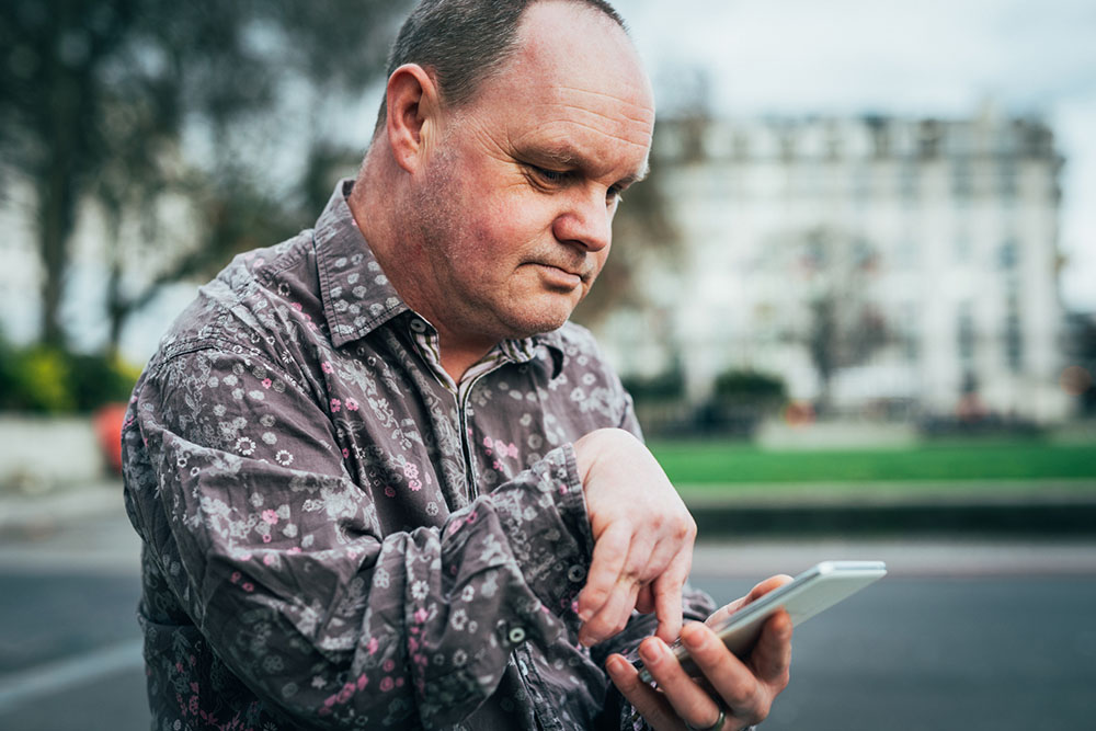 Middle aged man navigating phone with arm disability